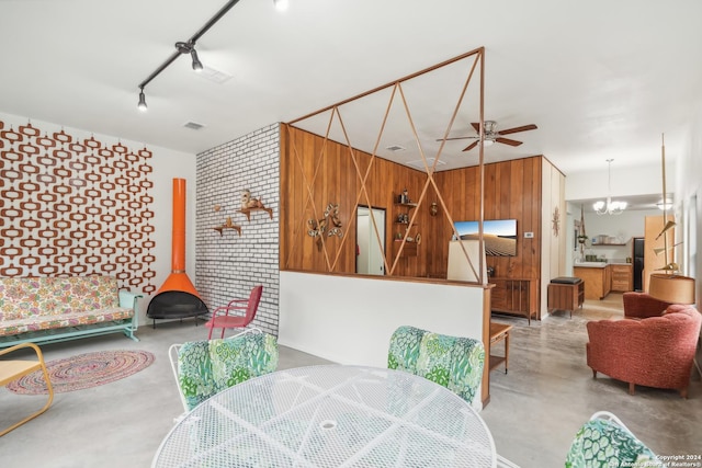 dining area featuring track lighting, ceiling fan with notable chandelier, and a wood stove