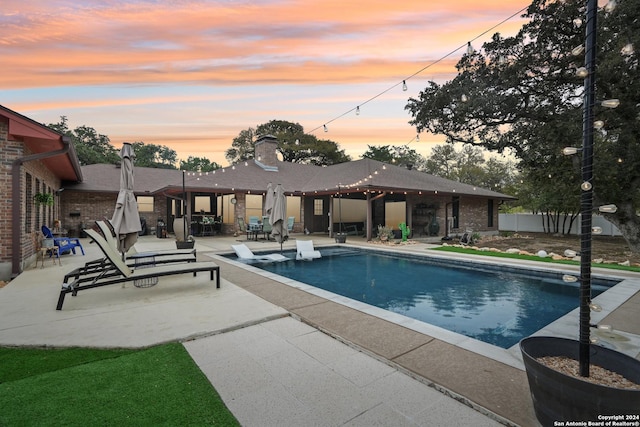 pool at dusk featuring a patio area