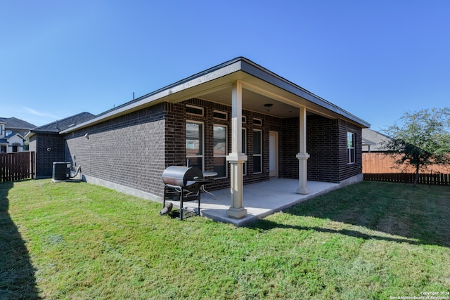 rear view of property featuring a lawn, cooling unit, and a patio