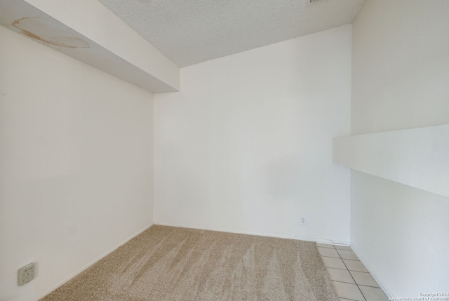 empty room featuring a textured ceiling and light carpet