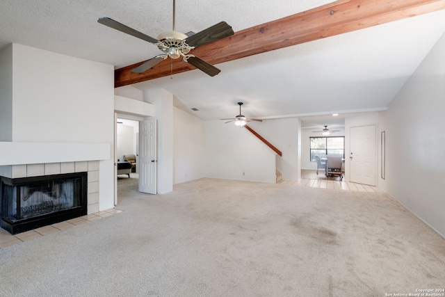 unfurnished living room with ceiling fan, light colored carpet, a fireplace, and a textured ceiling