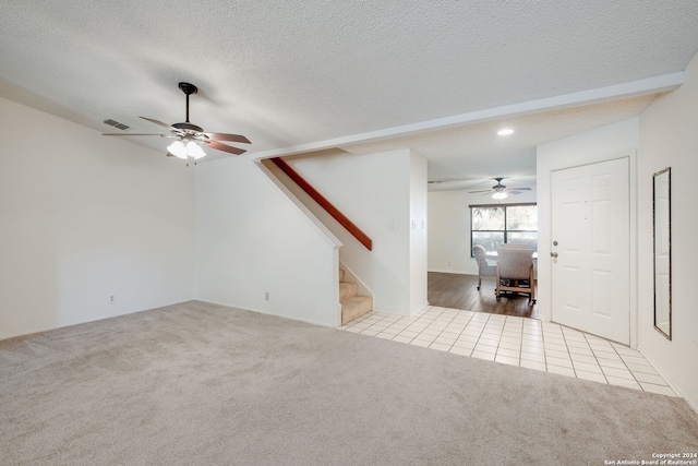 unfurnished living room with ceiling fan, light colored carpet, and a textured ceiling