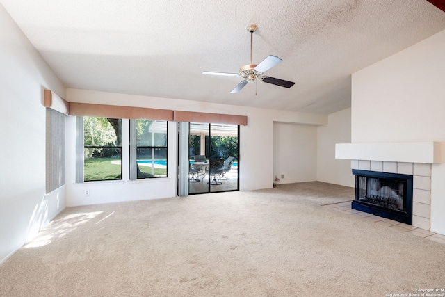 unfurnished living room featuring ceiling fan, a tile fireplace, light colored carpet, and a textured ceiling