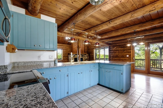 kitchen featuring decorative light fixtures, kitchen peninsula, log walls, and blue cabinetry