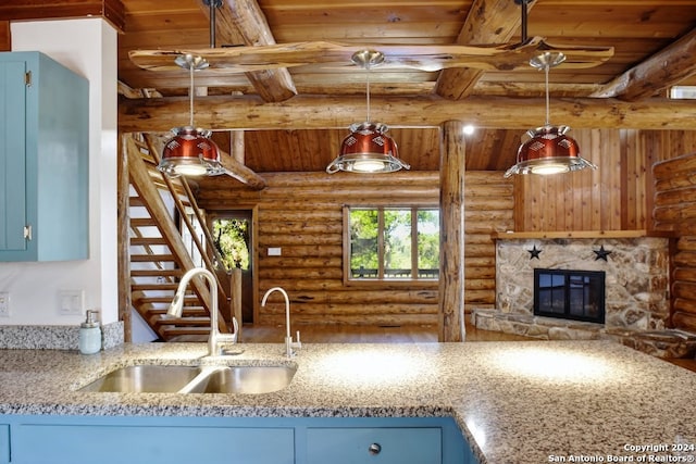 kitchen with decorative light fixtures, rustic walls, sink, a stone fireplace, and wooden ceiling