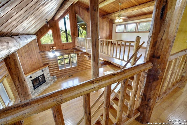 stairs featuring wooden ceiling, plenty of natural light, ceiling fan, and a stone fireplace