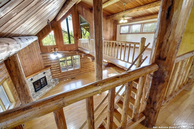 staircase featuring a glass covered fireplace, a healthy amount of sunlight, wooden ceiling, and lofted ceiling with beams