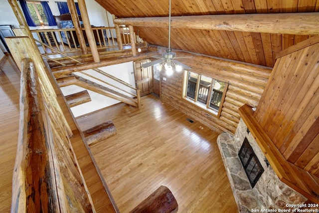 stairway featuring lofted ceiling with beams, a stone fireplace, wooden ceiling, wood finished floors, and a ceiling fan