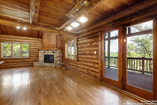 unfurnished living room with log walls, a stone fireplace, wood-type flooring, and wood ceiling