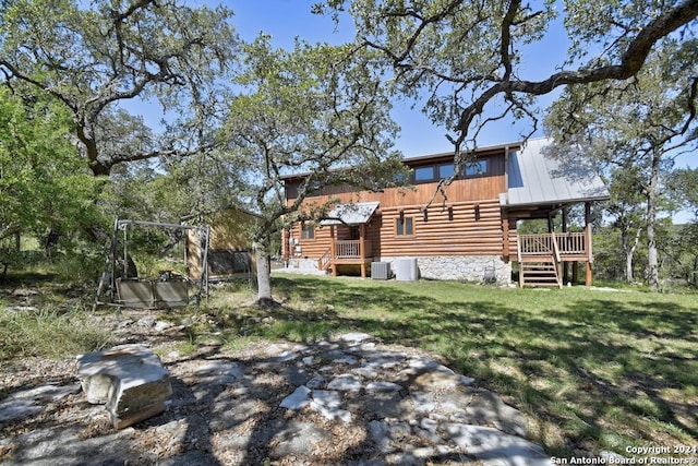 rear view of property featuring central air condition unit, a yard, and a deck