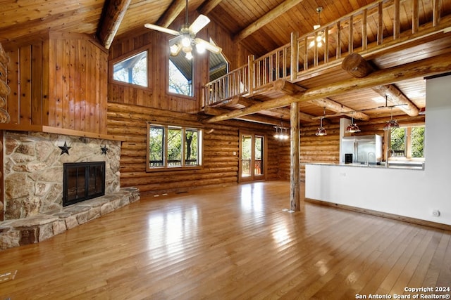 unfurnished living room with hardwood / wood-style floors, a ceiling fan, high vaulted ceiling, beam ceiling, and a fireplace