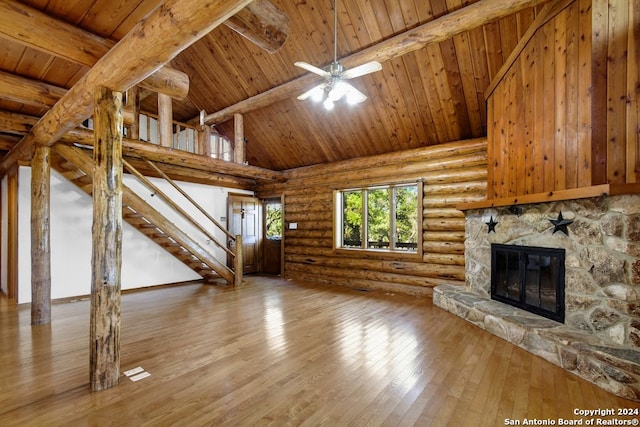 unfurnished living room featuring stairs, beam ceiling, light wood-style flooring, a fireplace, and high vaulted ceiling