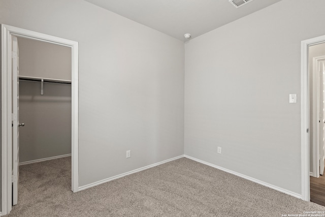 unfurnished bedroom with carpet flooring, a walk in closet, and a closet