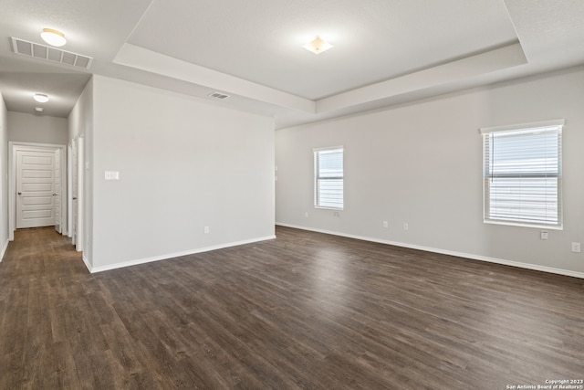 empty room featuring dark hardwood / wood-style floors and a tray ceiling