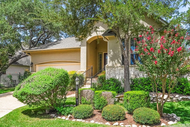 view of front of home with an attached garage, fence, and stucco siding