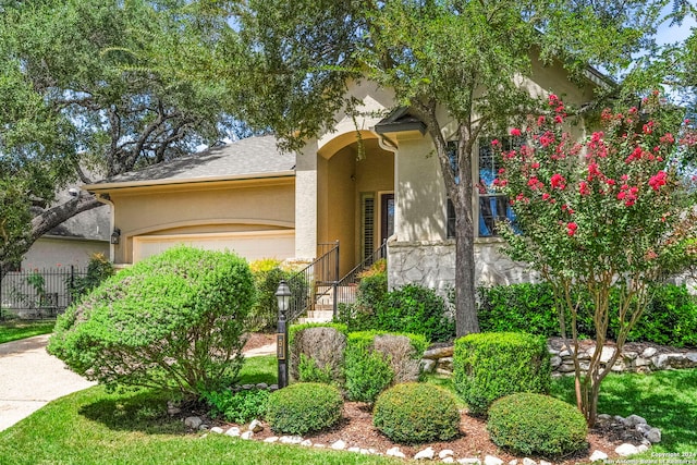 view of front facade with stucco siding, a garage, and fence