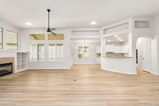 unfurnished living room with light wood-type flooring, baseboards, ceiling fan, and a tiled fireplace