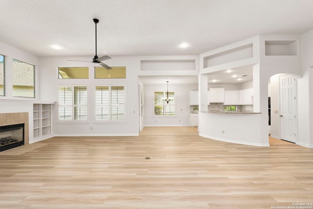 unfurnished living room featuring a fireplace, baseboards, light wood-type flooring, and a ceiling fan