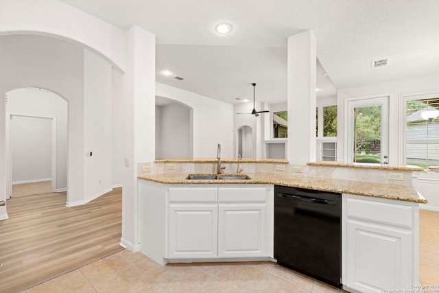 kitchen with black dishwasher, white cabinetry, a sink, and light stone countertops