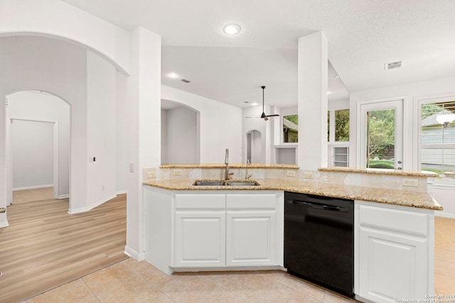 kitchen with black dishwasher, light stone countertops, arched walkways, and a sink