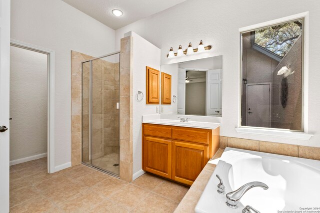 bathroom with tile patterned flooring, a garden tub, a stall shower, vanity, and a ceiling fan