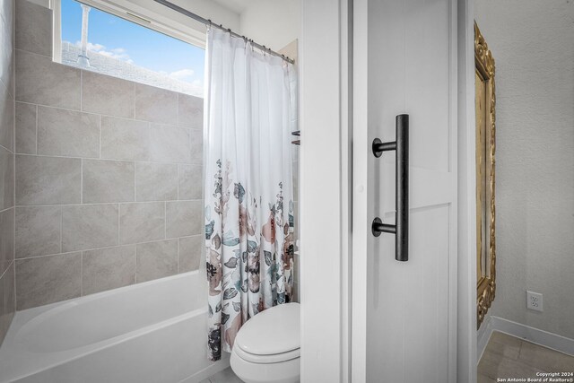 bathroom featuring shower / bath combo with shower curtain, tile patterned flooring, and toilet