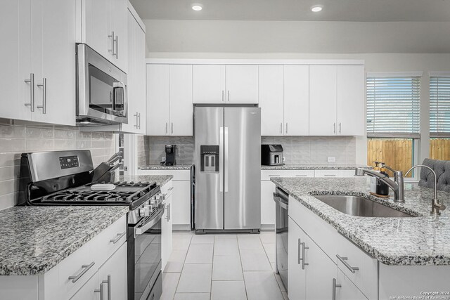 kitchen featuring light stone counters, stainless steel appliances, sink, and white cabinets