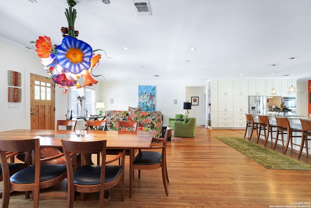 dining space with crown molding and light hardwood / wood-style flooring