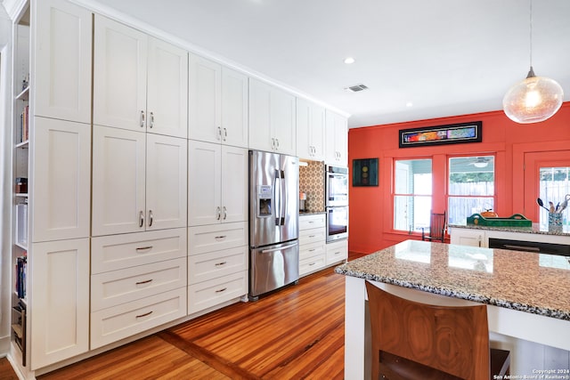 kitchen featuring light wood-type flooring, appliances with stainless steel finishes, and pendant lighting