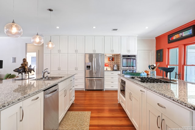 kitchen with light wood-type flooring, white cabinetry, decorative light fixtures, stainless steel appliances, and sink