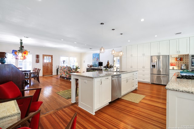 kitchen featuring appliances with stainless steel finishes, a center island with sink, white cabinets, and pendant lighting