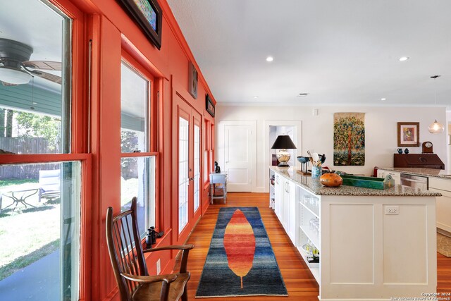 kitchen featuring decorative light fixtures, light stone counters, ceiling fan, white cabinets, and light hardwood / wood-style floors