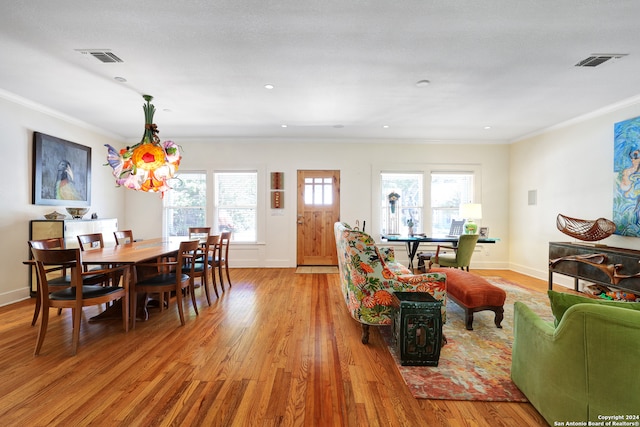 dining room with crown molding, plenty of natural light, and light wood-type flooring