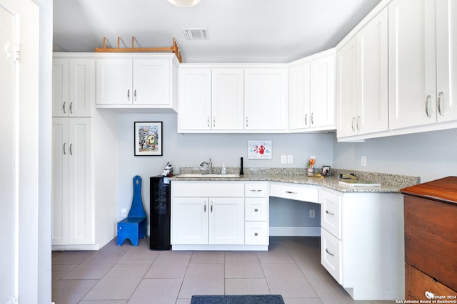 kitchen featuring white cabinetry, light stone counters, sink, and light tile patterned flooring