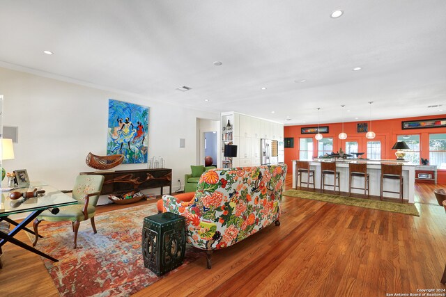 living room with a healthy amount of sunlight, ornamental molding, and hardwood / wood-style flooring