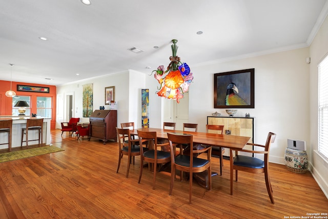 dining space featuring hardwood / wood-style floors, crown molding, and a healthy amount of sunlight