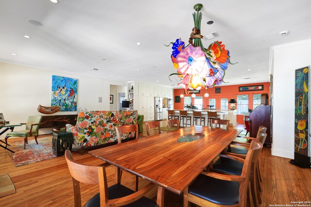 dining space with ornamental molding, wood-type flooring, and a notable chandelier