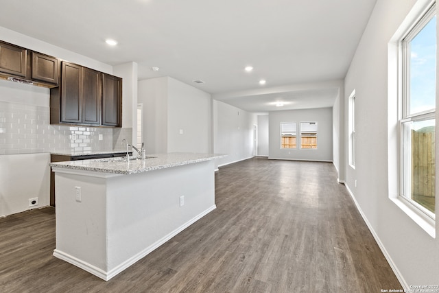 kitchen featuring dark hardwood / wood-style floors, dark brown cabinets, backsplash, an island with sink, and sink