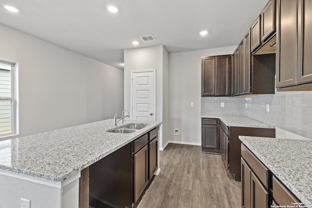 kitchen featuring tasteful backsplash, hardwood / wood-style flooring, sink, and light stone countertops