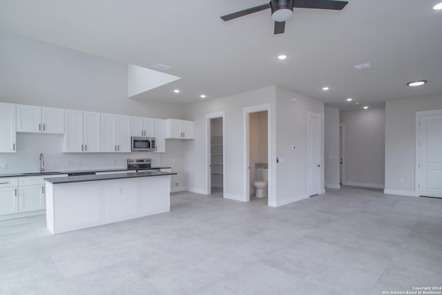 kitchen featuring stainless steel appliances, white cabinetry, sink, ceiling fan, and a kitchen island