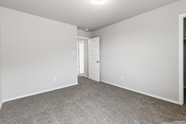 unfurnished room with a textured ceiling and dark carpet