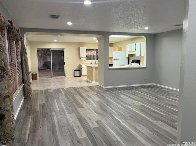 unfurnished living room featuring a textured ceiling and light hardwood / wood-style floors