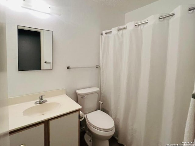 bathroom with vanity, curtained shower, toilet, and a textured ceiling