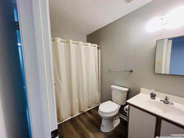 full bathroom with toilet, a textured ceiling, vanity, and wood finished floors