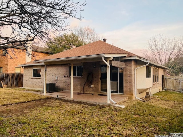 rear view of house with brick siding, central AC, a lawn, and fence