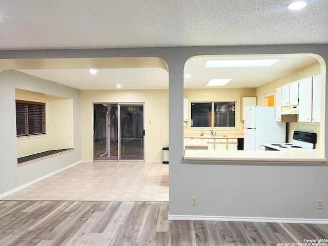 kitchen featuring baseboards, freestanding refrigerator, wood finished floors, electric range, and a sink