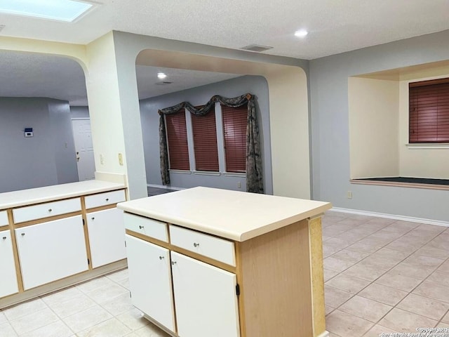 kitchen featuring visible vents, a center island, recessed lighting, white cabinets, and light countertops