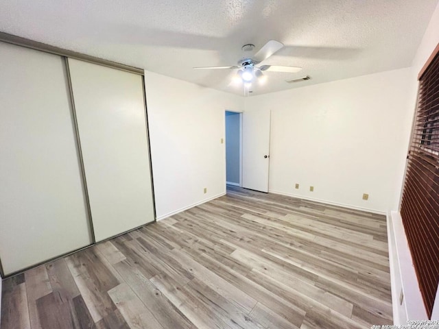 unfurnished bedroom with visible vents, ceiling fan, a closet, a textured ceiling, and light wood-type flooring