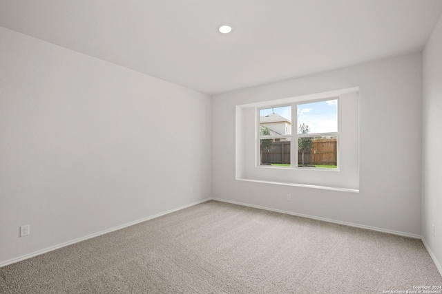 empty room featuring light carpet, recessed lighting, and baseboards