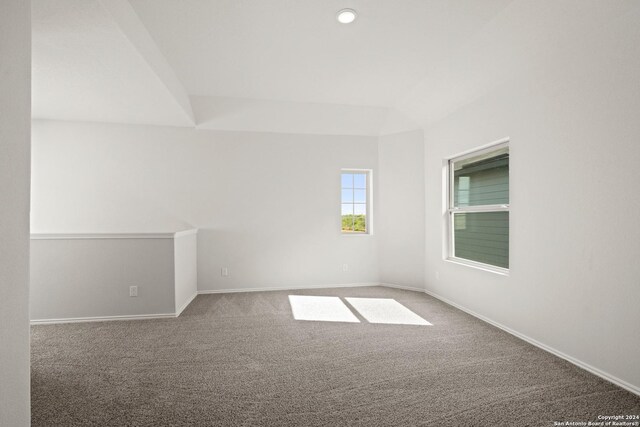 unfurnished room featuring lofted ceiling and carpet flooring